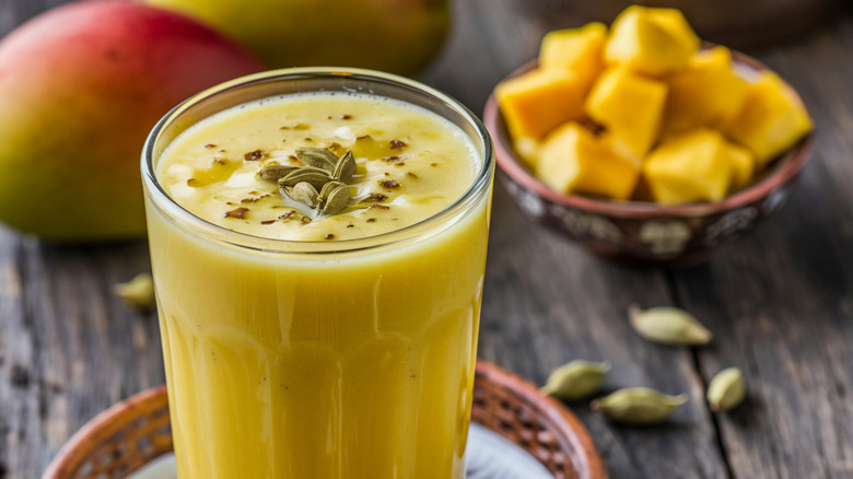 mango lassi in a glass with mango in background