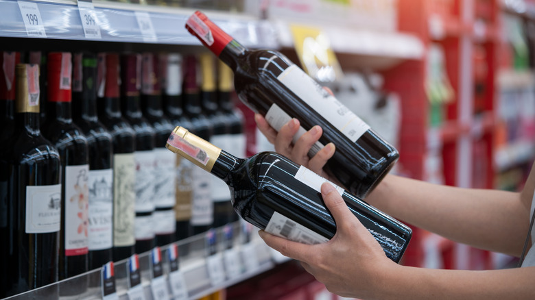 A person comparing two bottles of red wine