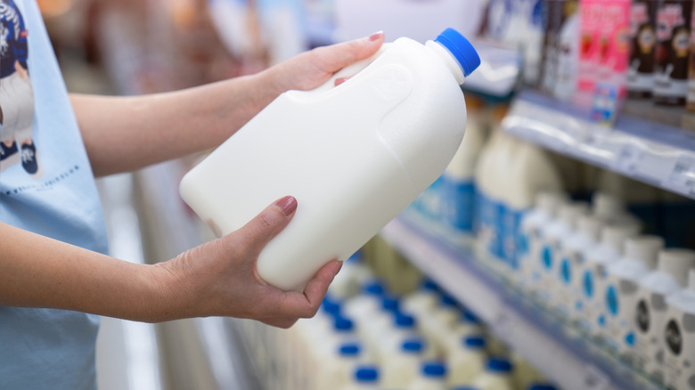 Someone holding a gallon of milk in the supermarket